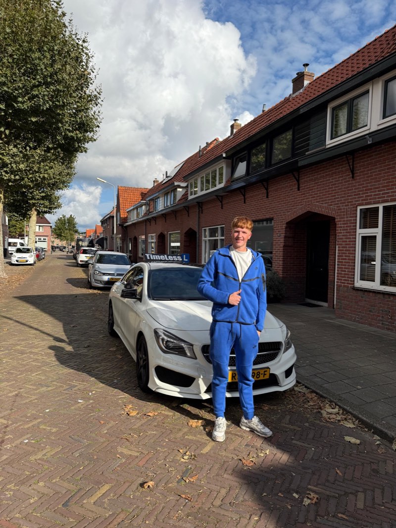 Geslaagde leerling in blauwe kleding voor de lesauto