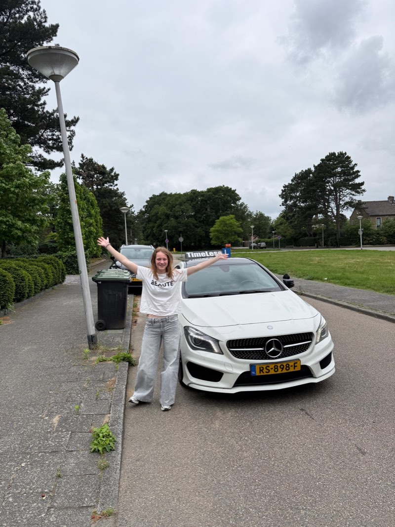 Geslaagde leerling viert haar rijbewijs met haar armen in de lucht