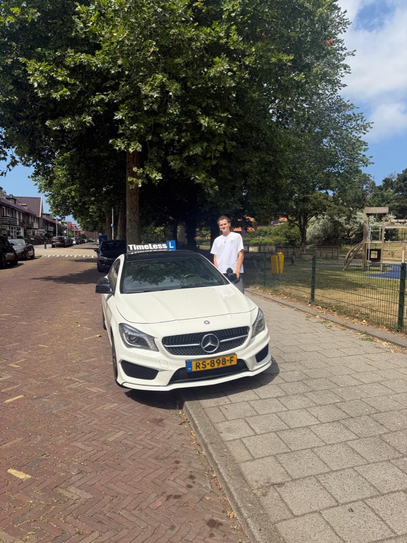 Geslaagde leerling naast de TimeLess-auto onder een boom